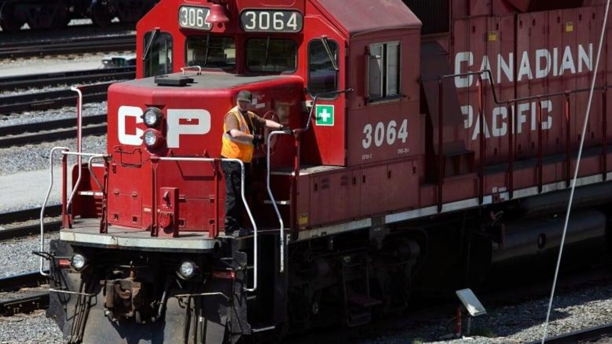 Un travailleur debout près de la cabine du conducteur de la locomotive d'un train du Canadien Pacifique.