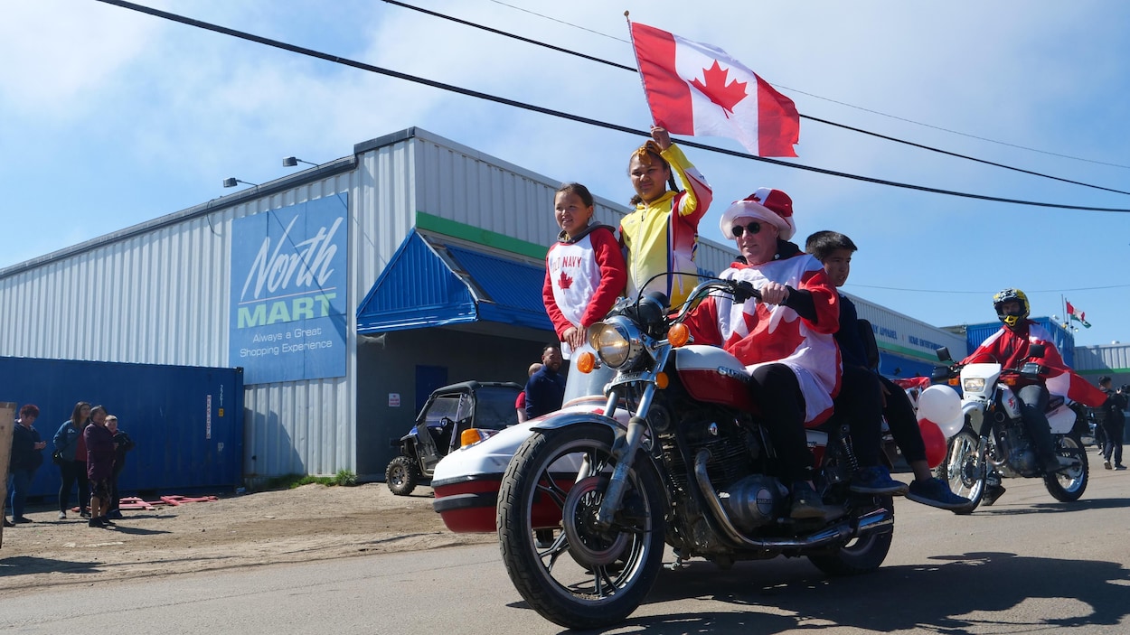 Un homme en moto fait flotter un drapeau du Canada lors de la parade.