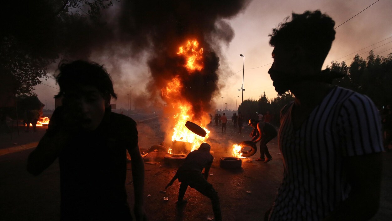 Des manifestants alimentent, au milieu de la route, un brasier avec des pneus.