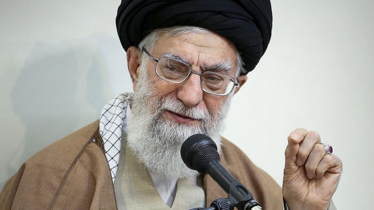 Plan rapproché de l'ayatollah Khamenei qui parle dans un micro en levant la main.