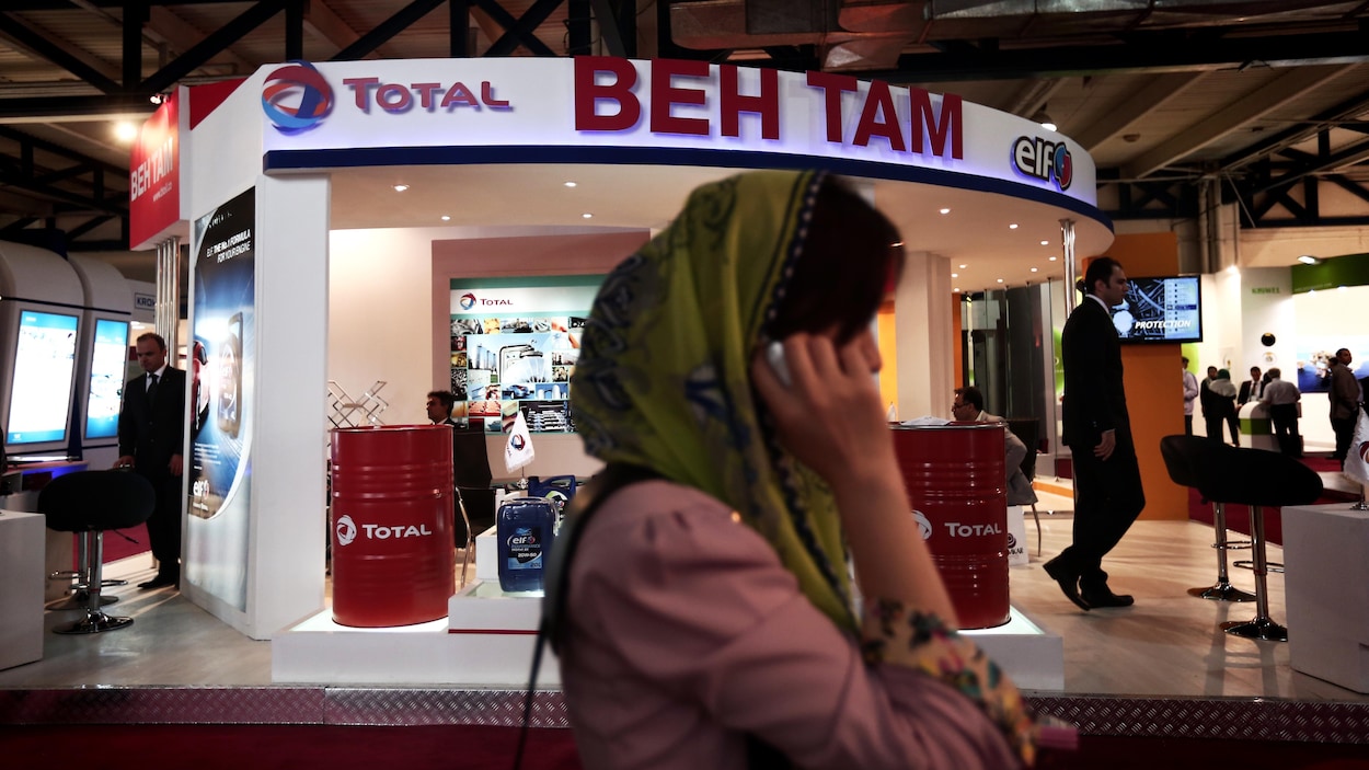 Une femme parle au téléphone en passant devant un kiosque de la pétrolière Total. Une femme parle au téléphone en passant devant un kiosque de la pétrolière Total.