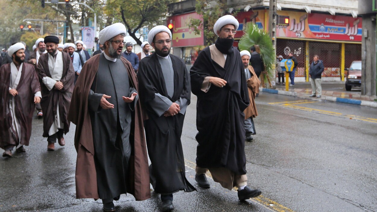 Des mollahs marchent dans la rue en discutant.