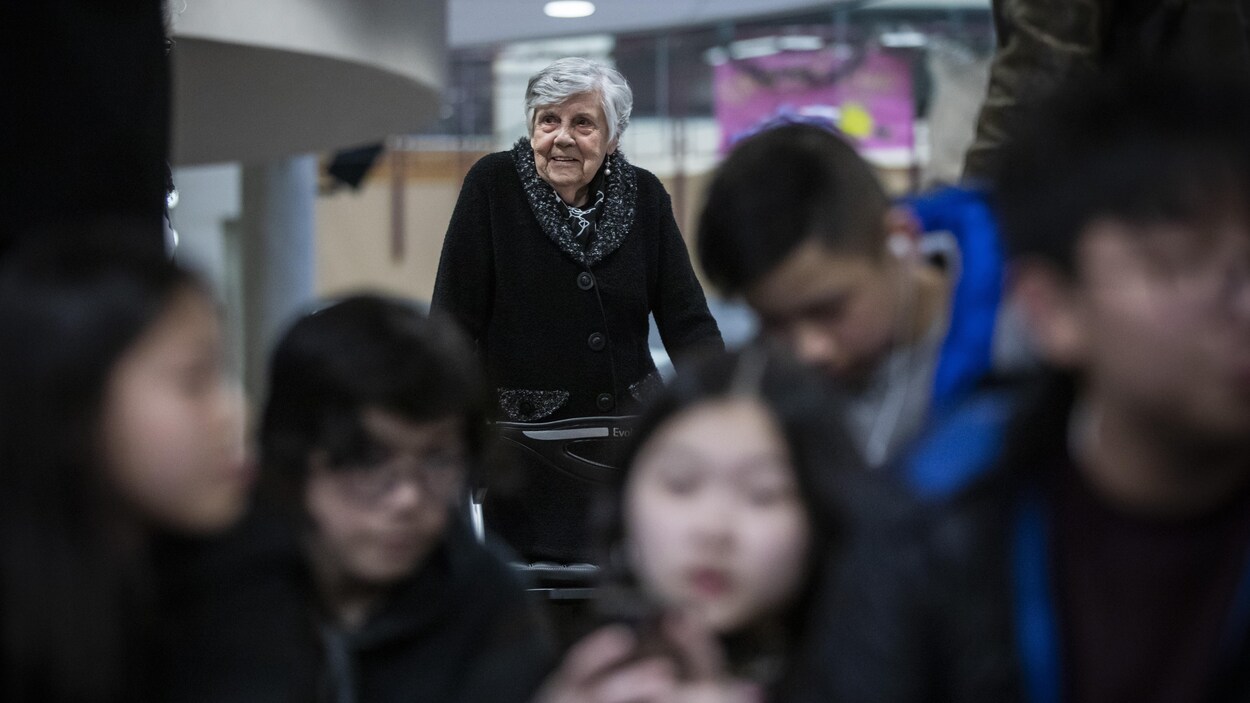 Irene Russell, âgée de 99 ans, dans les couloirs d'une école secondaire avec des élèves adolescents.