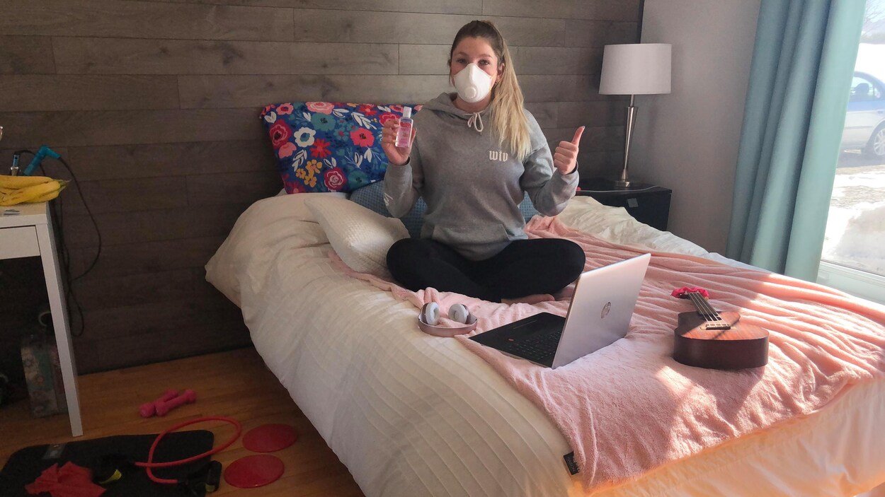 Juliette Moses est assise sur son lit, portant un masque.
