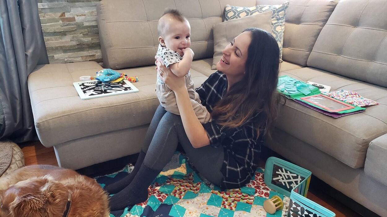 Une mère tient son bébé dans ses bras, dans son salon.