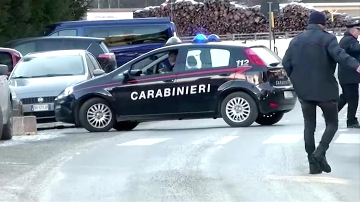 La voiture de police est stationnée en travers de la route, devant une pile de bois de chauffage.