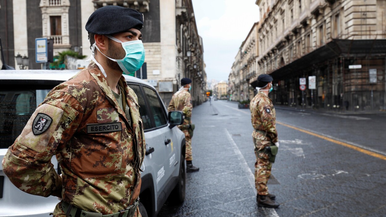 Des soldats italiens portant des masques gardent une rue déserte.