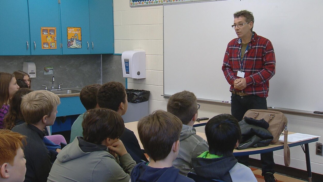 Un homme devant un groupe d'élèves dans une classe d'école.
