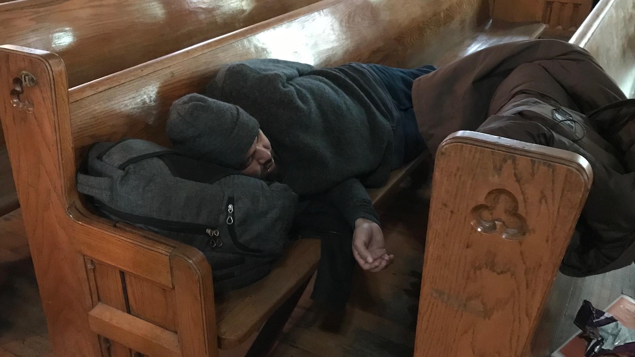 Une personne est allongée sur un banc, la tête appuyée sur son sac. Une personne est allongée sur un banc, la tête appuyée sur son sac.