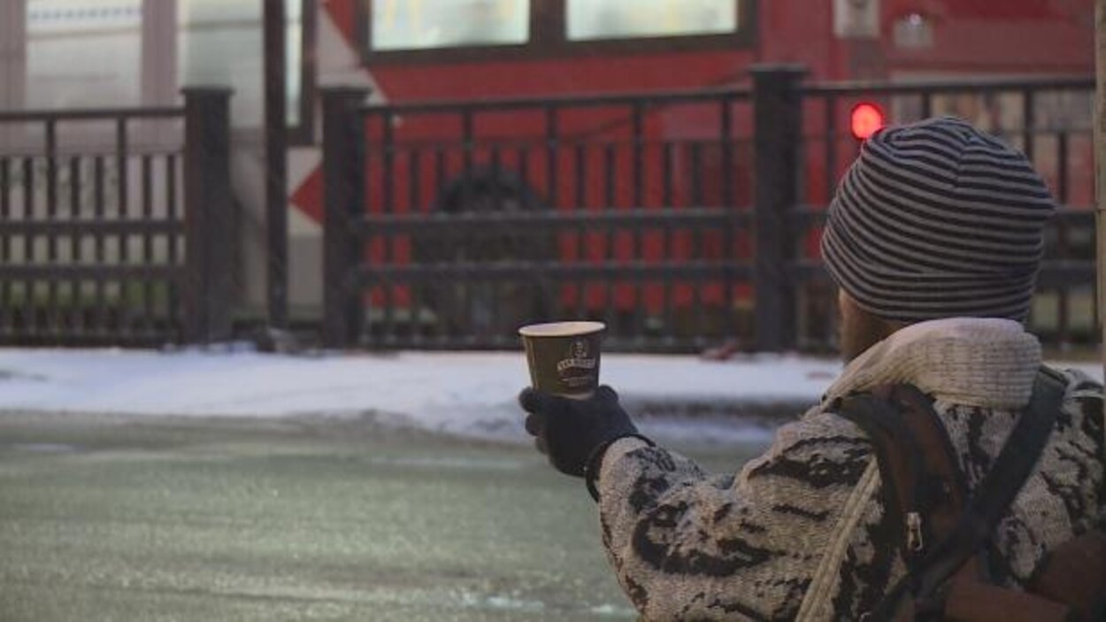 Un homme vu de dos dans la rue qui tend un verre pour recevoir de l'argent. Un homme vu de dos dans la rue qui tend un verre pour recevoir de l'argent.
