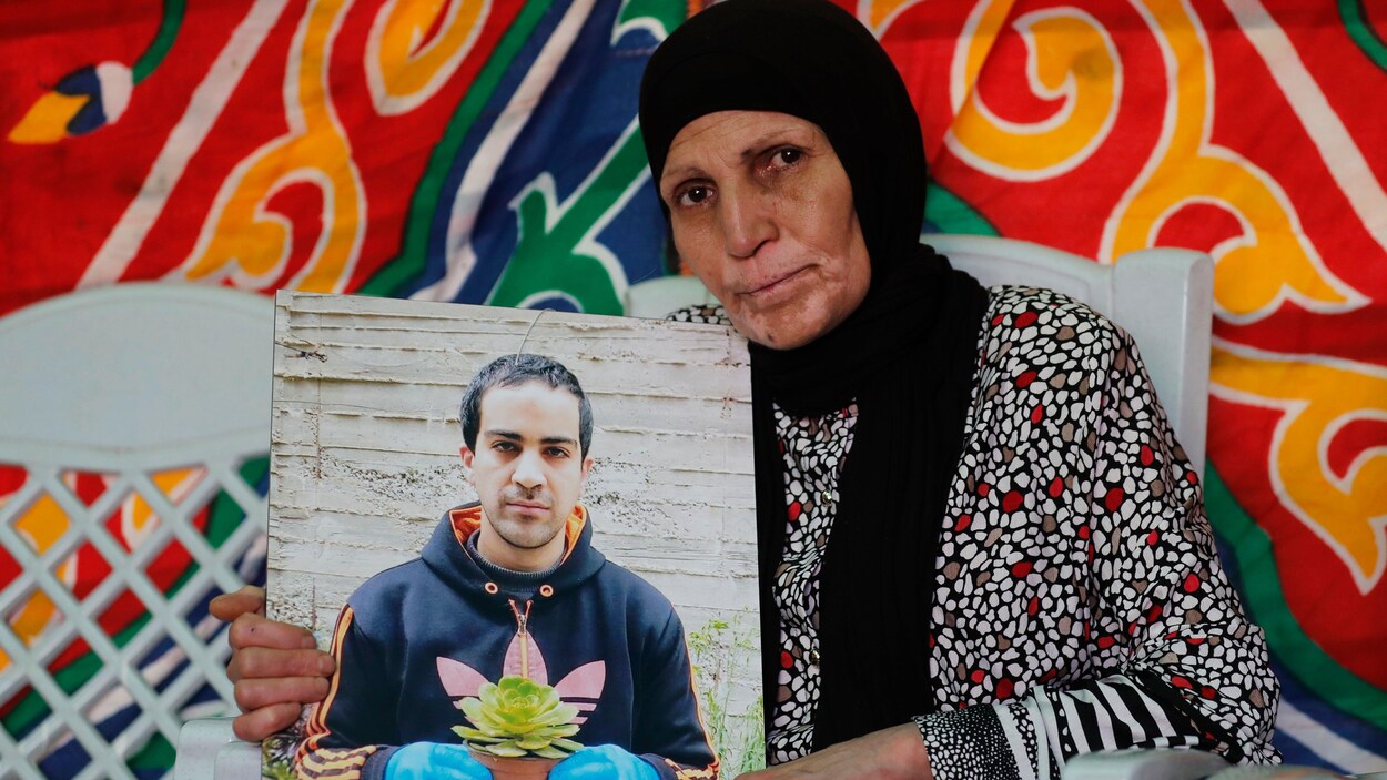 La mère d'Iyad Hallak tient dans ses mains une photo de son fils. On le voit tenir un pot de fleur.