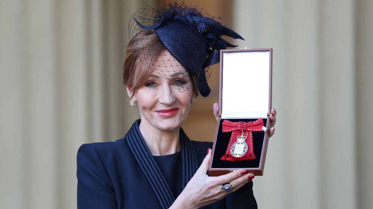 J.K. Rowling en habits élégants arbore une médaille au palais de Buckingham. J.K. Rowling en habits élégants arbore une médaille au palais de Buckingham.