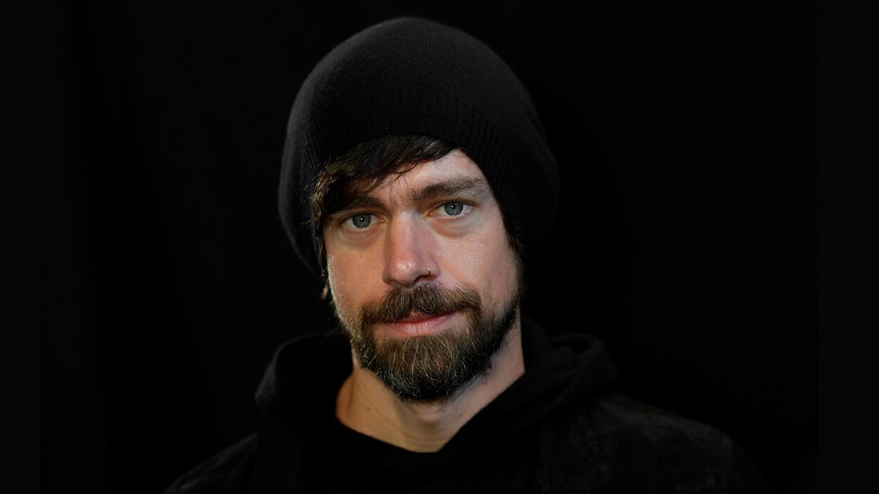 Jack Dorsey, un homme barbu avec une tuque, regarde la caméra dans une photo studio.