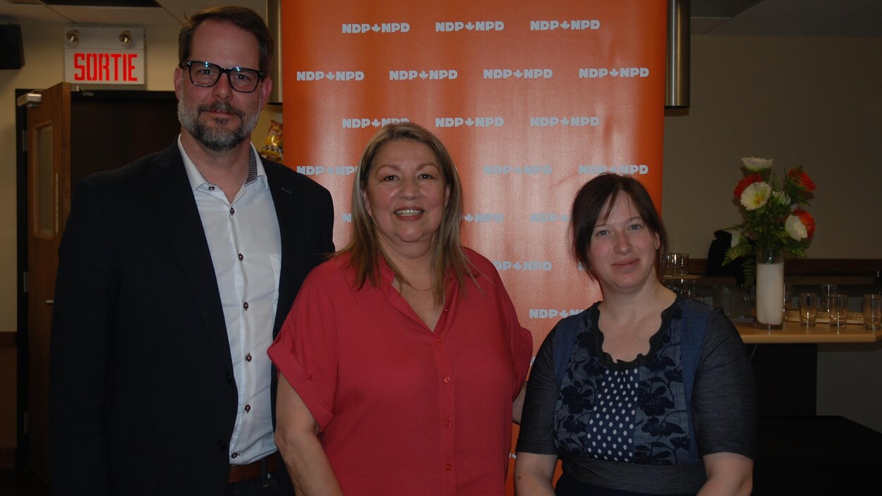 Alexandre Boulerice et Christine Moore posent avec une femme devant une affiche du NPD.