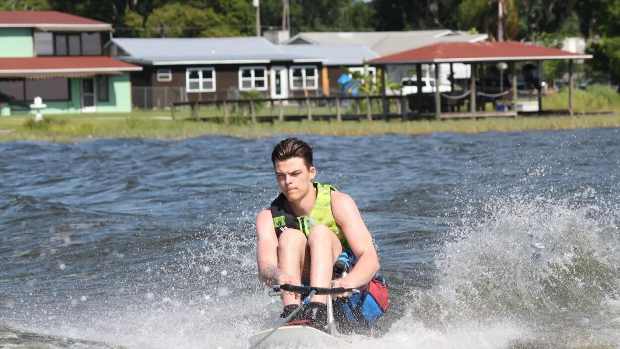 Un jeune homme faisant du ski nautique assis sur un équipement spécialisé.