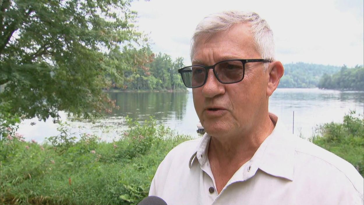 Jacques Laurin en entrevue devant une rivière et des arbres.