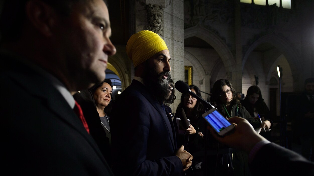 Le chef du Nouveau Parti démocratique (NPD) Jagmeet Singh tient une conférence de presse entouré de journalistes, un micro et un téléphone cellulaire brandis dans sa direction.