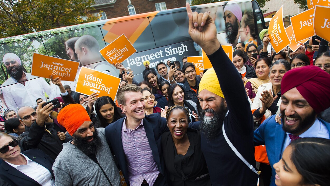 Jagmeet Singh lève un doigt au ciel, entouré de personnes qui sourient.