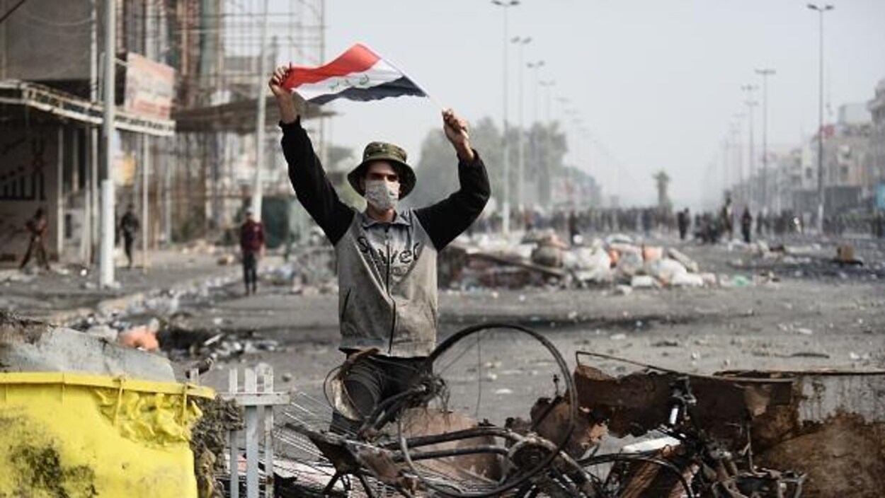 Un manifestant irakien porte le drapeau national à Najaf, ville sainte chiite du sud de l'Irak le 1er décembre 2019.