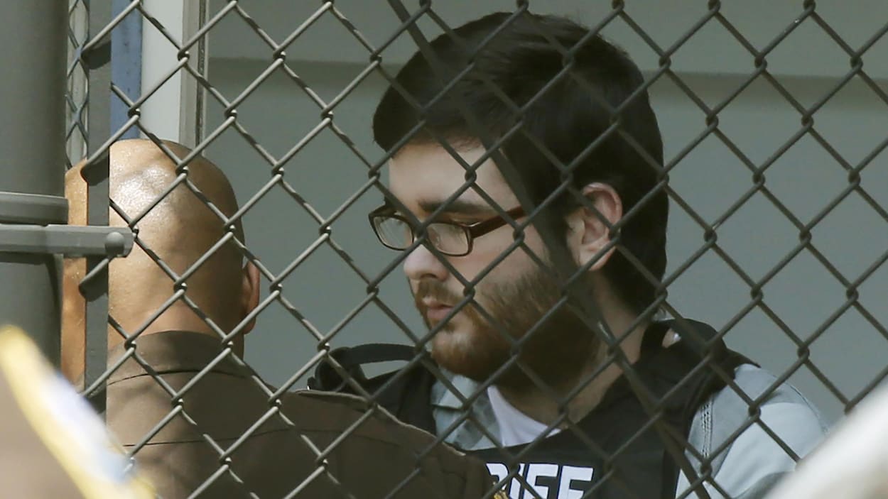James Alex Fields marche derrière une grille.