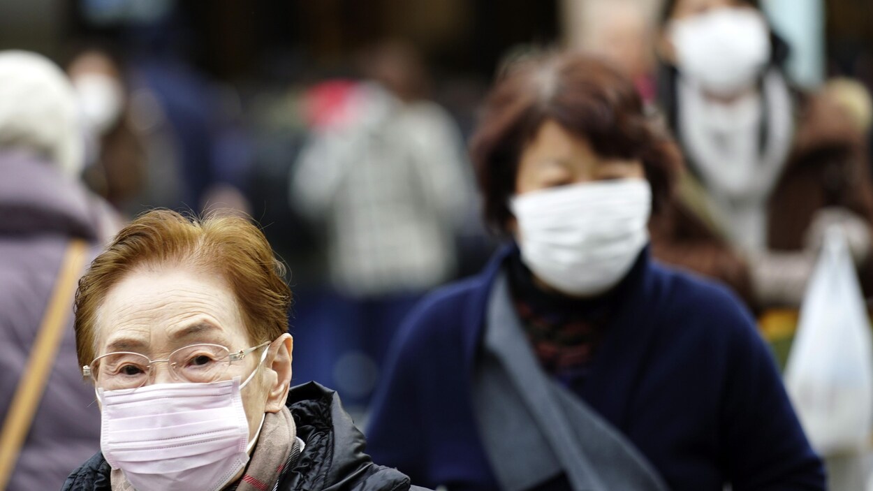 Deux passantes à Tokyo portant des masques blancs sur leur visage.