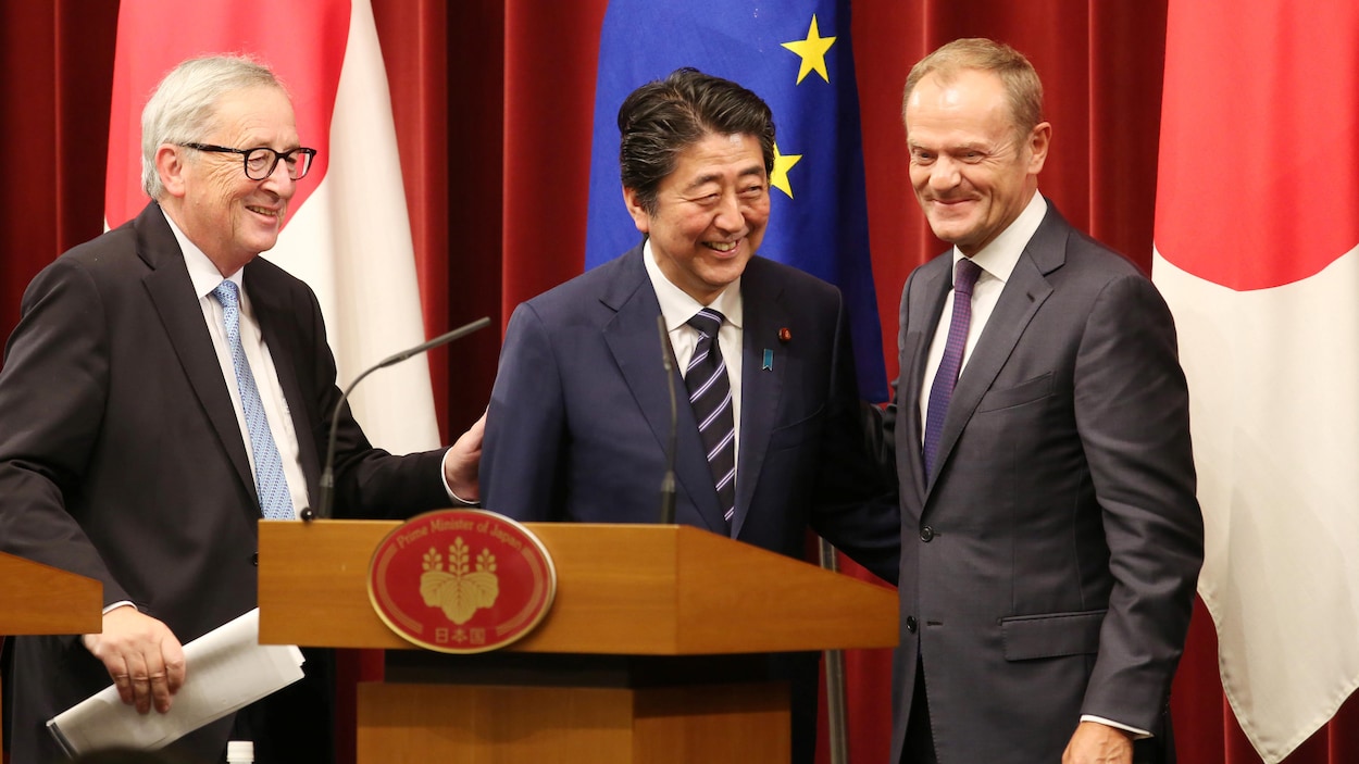 Les trois hommes sont tout sourire sur l'estrade.