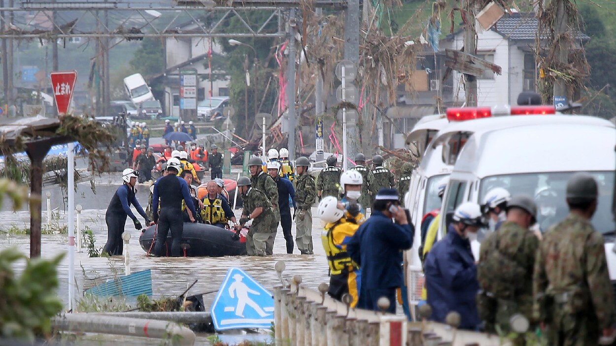 Des militaires et des civils, dans l'eau jusqu'aux genoux, lors d'une opération d’évacuation.