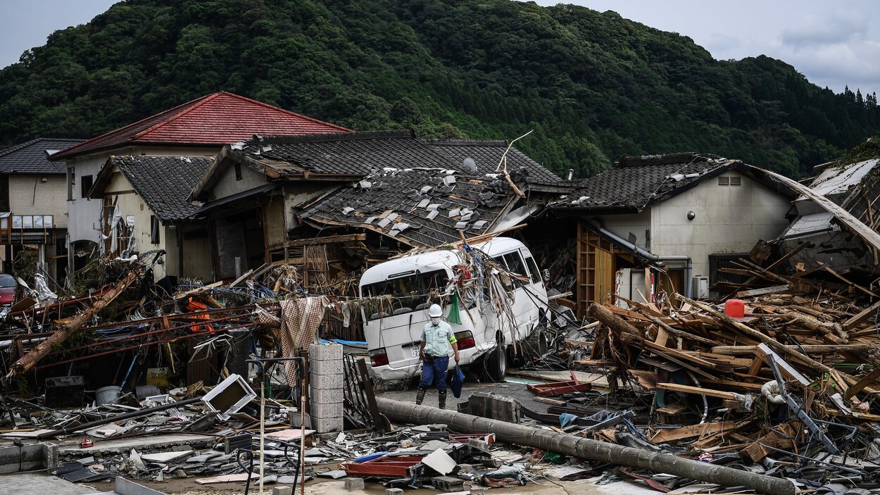 Un homme marche devant des maisons endommagées après des pluies torrentielles et des inondations au Japon.