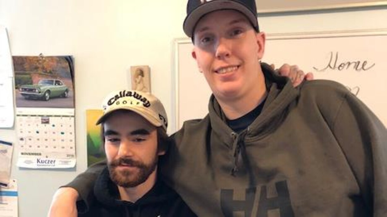 Deux hommes se tenant par les épaules posent pour la caméra.