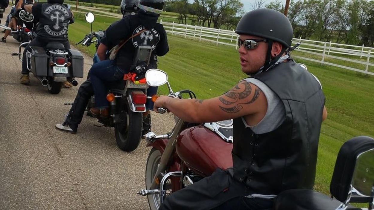 Jared Robertson sur une moto porte une combinaison de motard et se trouve sur une fille avec plusieurs autres motards devant lui. Jared Robertson sur une moto porte une combinaison de motard et se trouve sur une fille avec plusieurs autres motards devant lui.