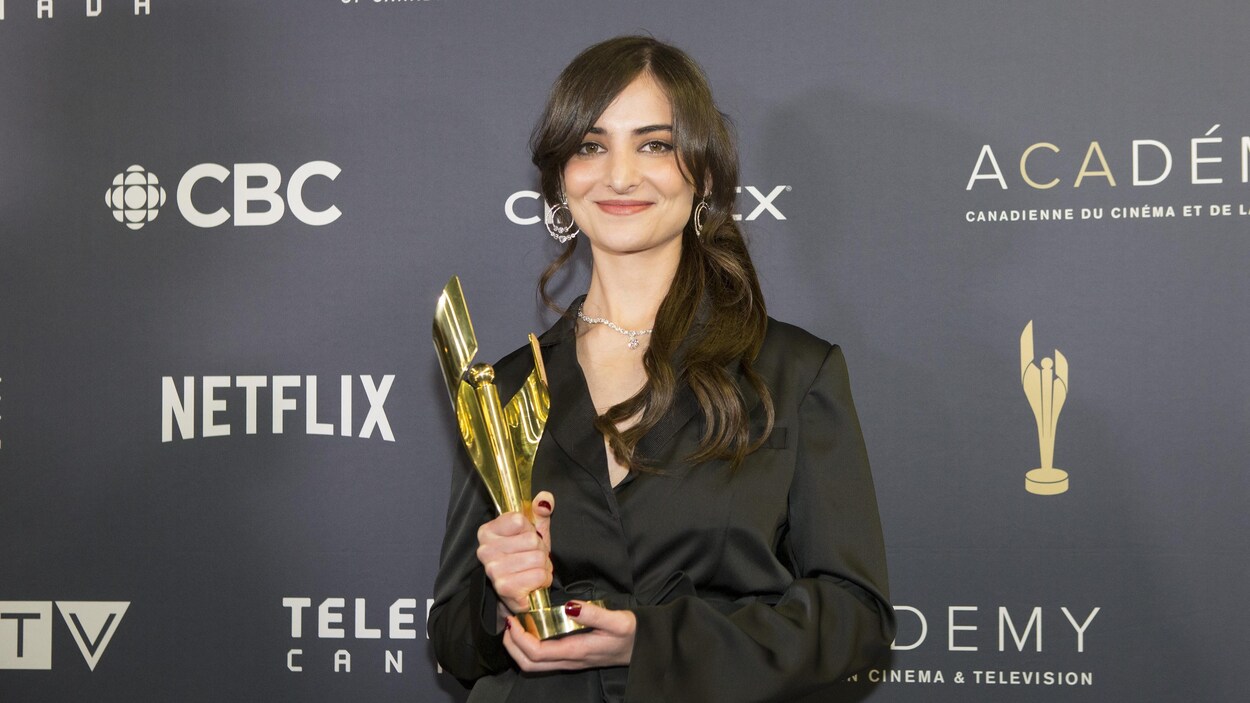 La femme pose en souriant avec son trophée.
