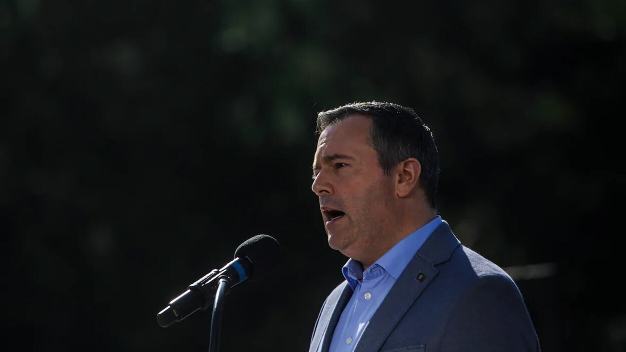 Plan moyen de profil de Jason Kenney parlant au microphone.