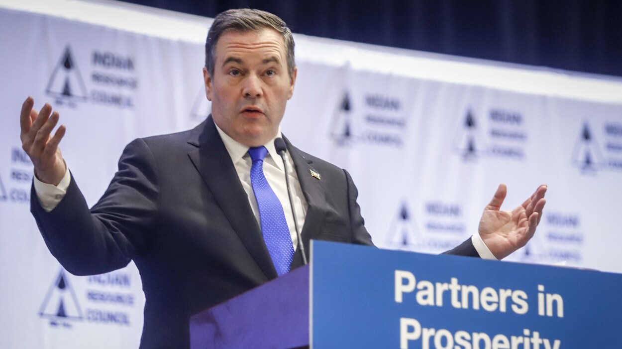 Jason Kenney est au podium. Il lève les bras en l'air en parlant.
