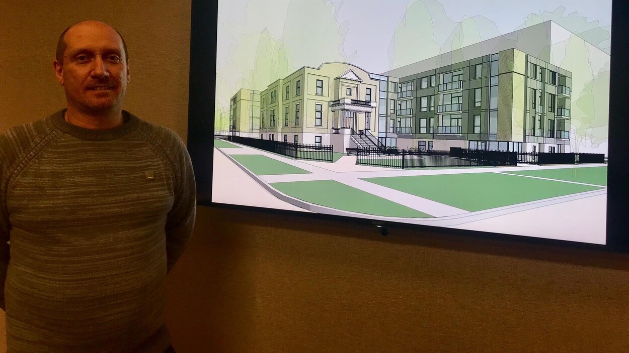 un homme debout et près de lui une image d'un projet immobilier.