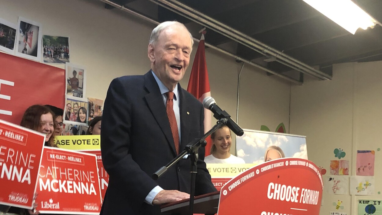 Jean Chrétien prend la parole derrière un lutrin avec un microphone lors d'un rassemblement de militant du Parti libéral du Canada.