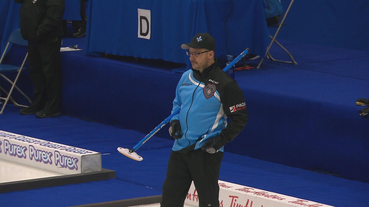 Un joueur de curling suit l'évolution de sa pierre des yeux.
