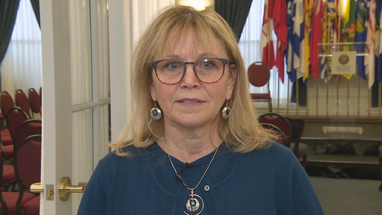 Plan moyen de Jean Teillet donnant une entrevue à l'arrière d'une salle de conférence.