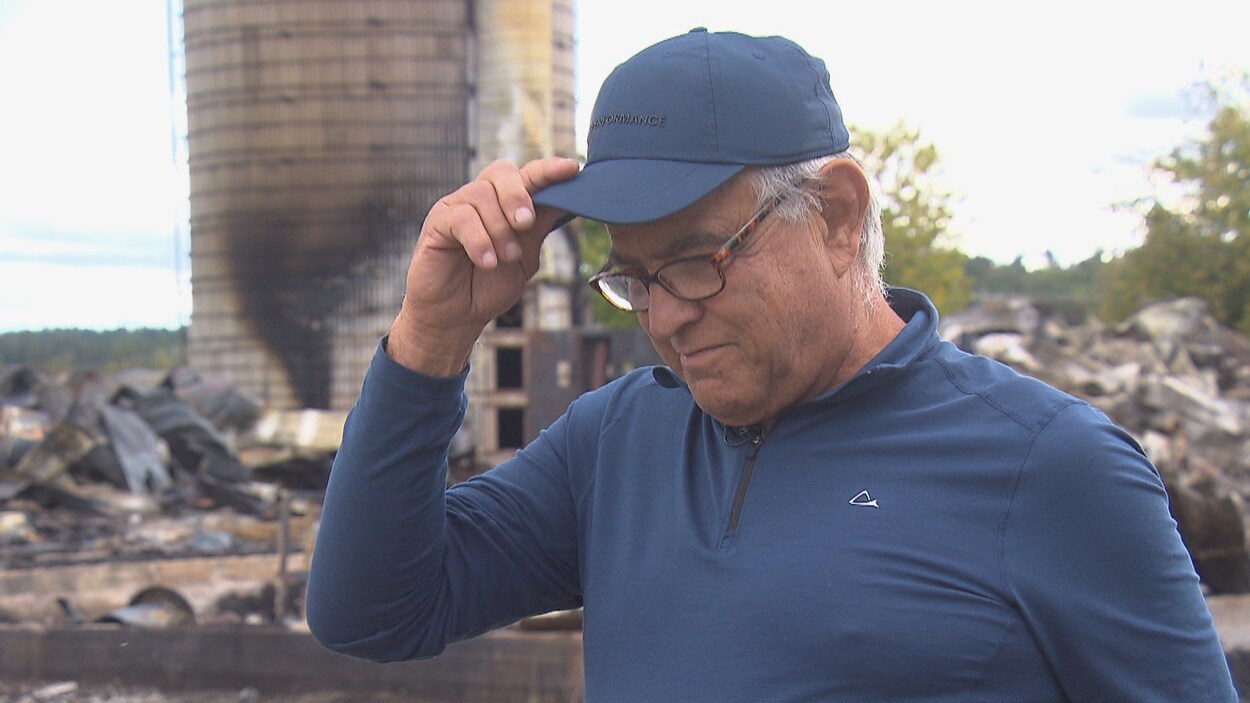 Jean-Guy Beaulieu regarde au sol devant les décombres de ses installations agricoles.