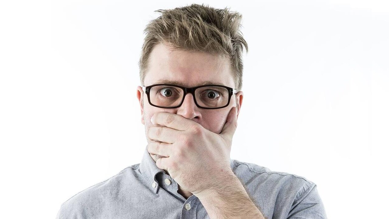Le chroniqueur a une main sur sa bouche et semble choqué par ce qu'il voit.
