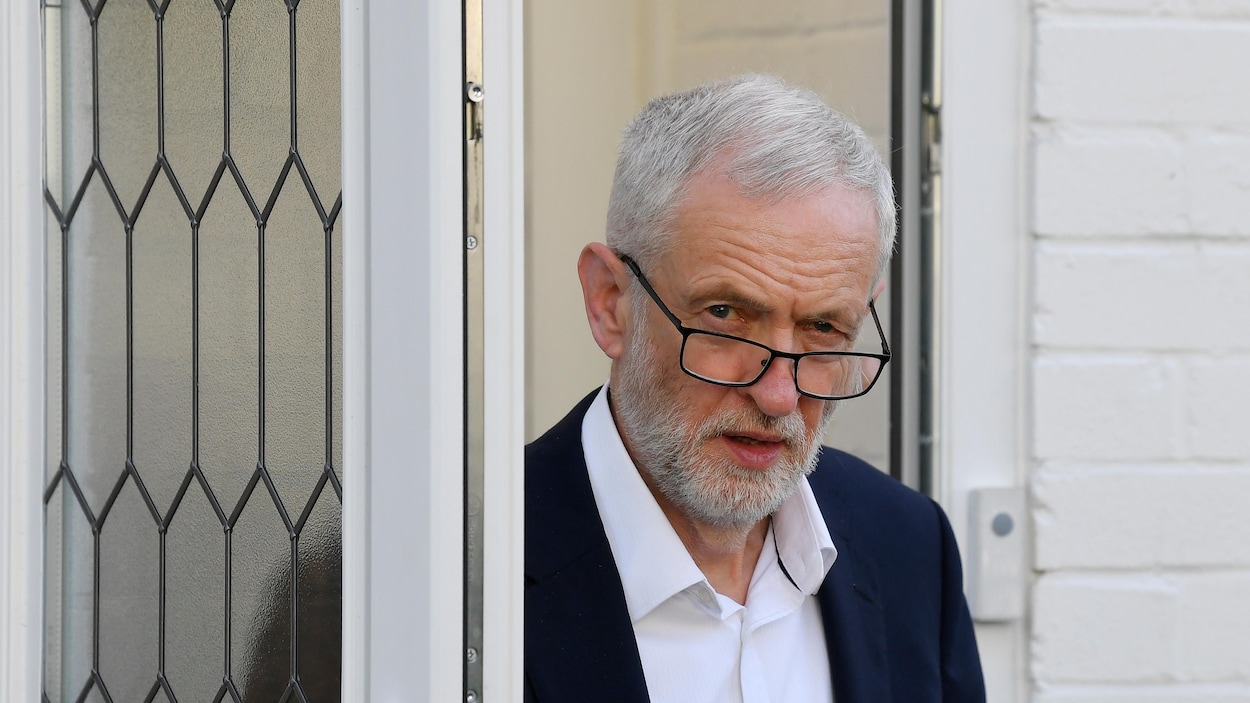 Jeremy Corbyn regarde par-dessus ses lunettes en franchissant une porte.