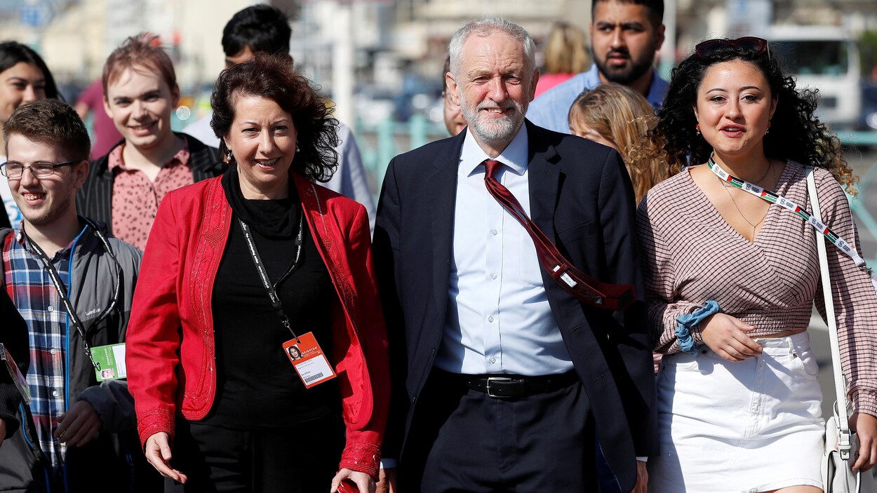 M. Corbyn marche, entouré de plusieurs militants.