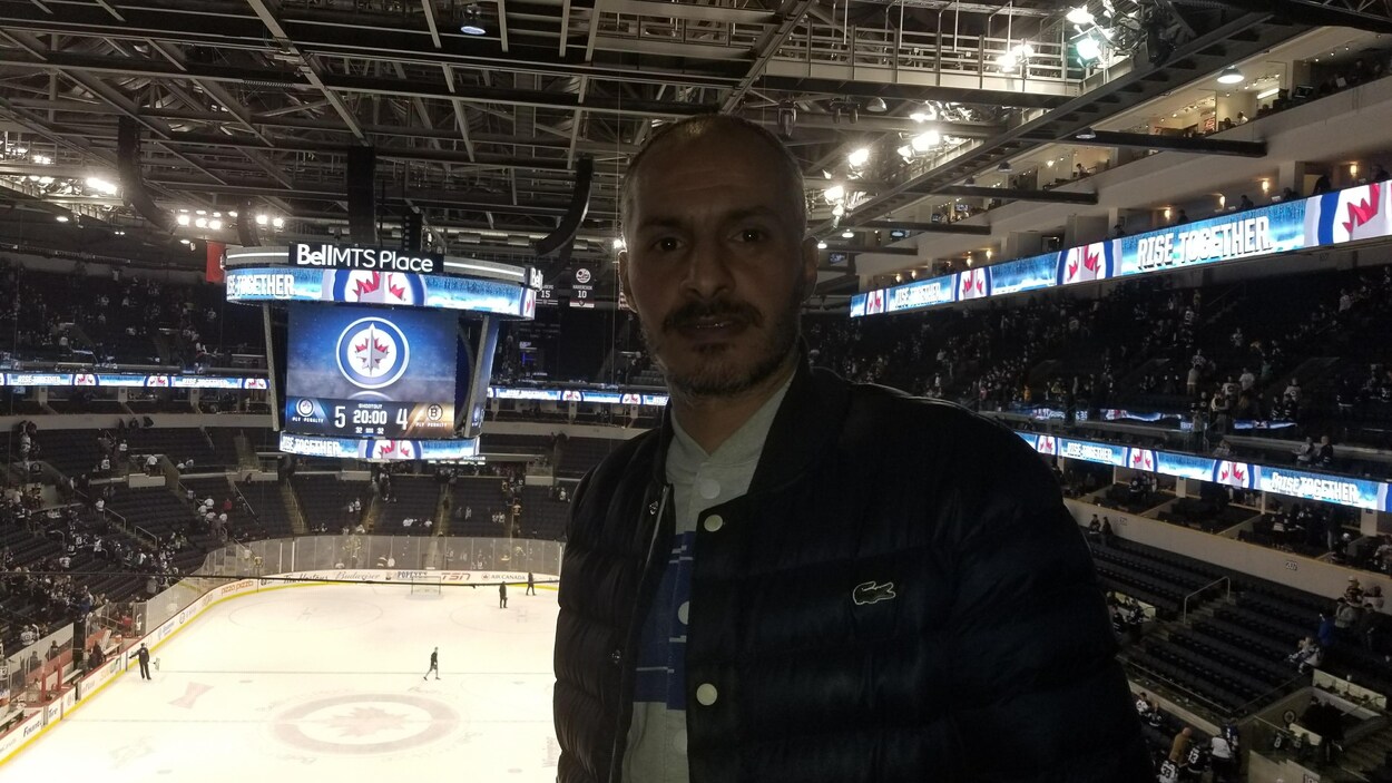 Un homme pose devant la glace d'une arena de hockey Un homme pose devant la glace d'une arena de hockey