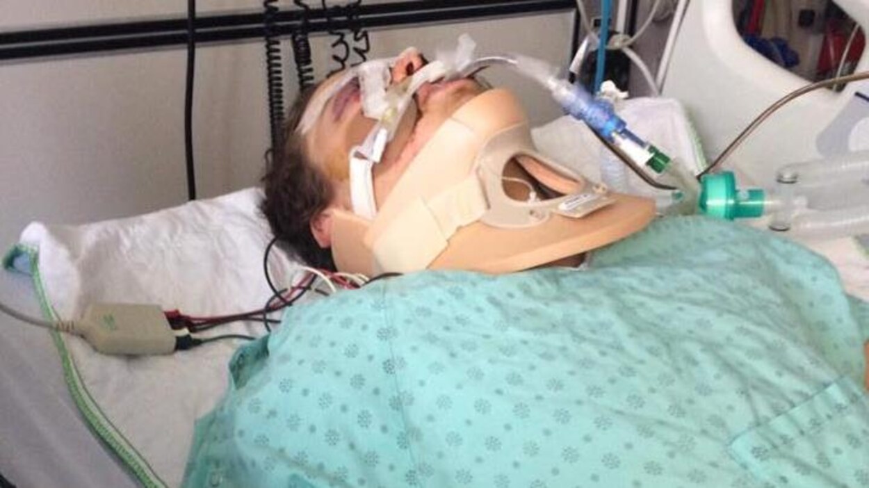 Le jeune homme fortement intubé est couché dans un lit d'hôpital en jaquette bleue