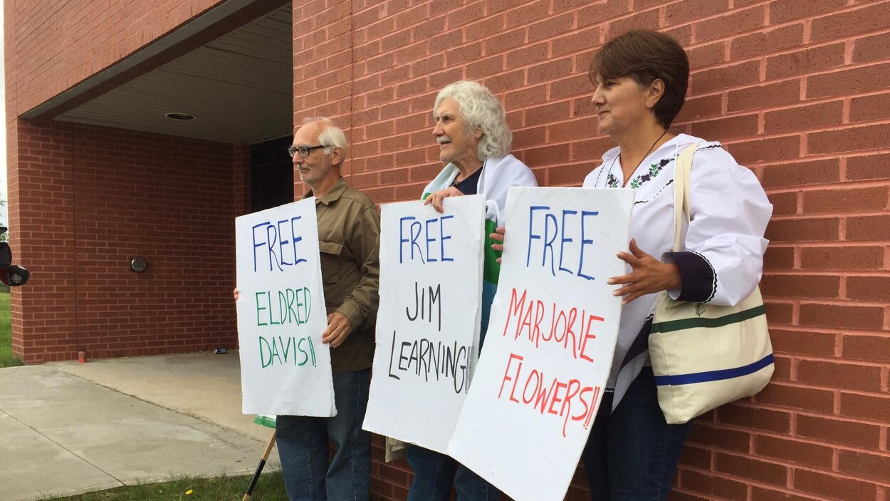 Trois protestants réclamant leur libération pendant une manifestation contre Muskrat Falls