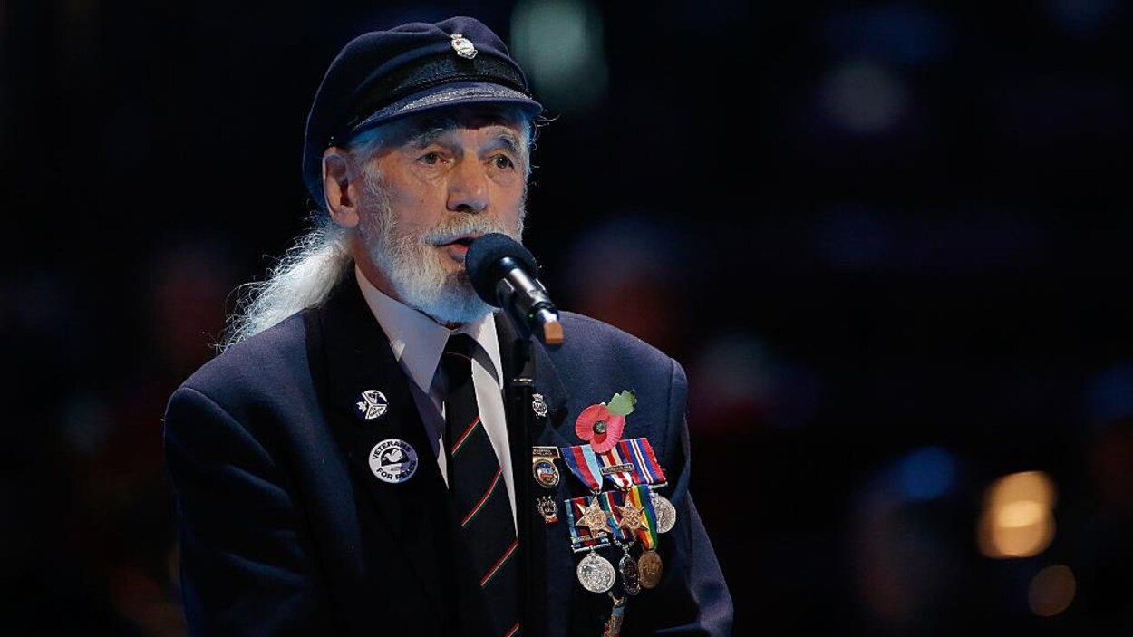 Jim Radford chante vêtu d'une veste ornée de nombreuses médailles militaires.
