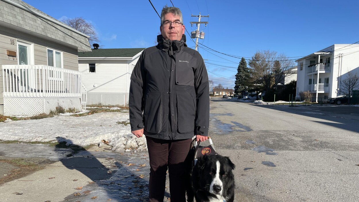 Jimmy Turgeon-Carrier se promène dans la rue avec son chien. Des plaques de glace se trouvent au sol.