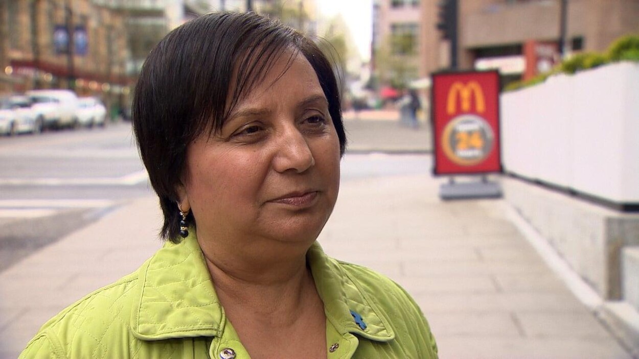Une femme aux cheveux foncés devant un restaurant McDonald's.