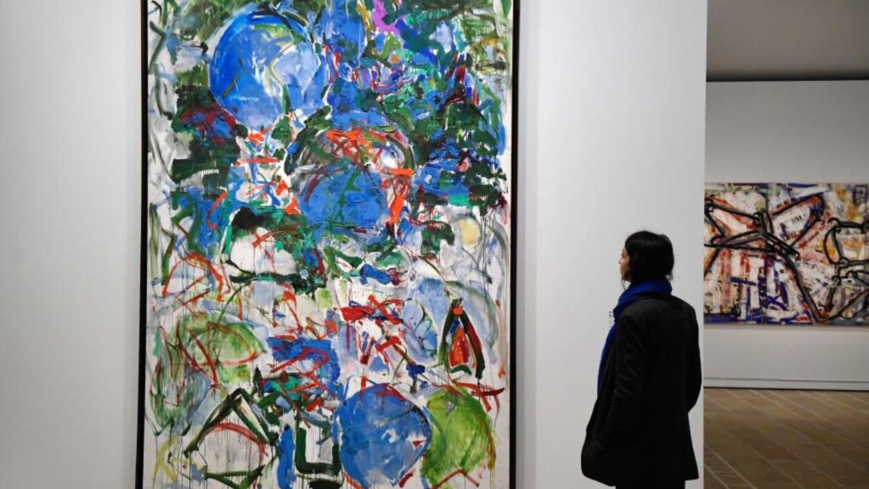 Une femme regarde une toile colorée.