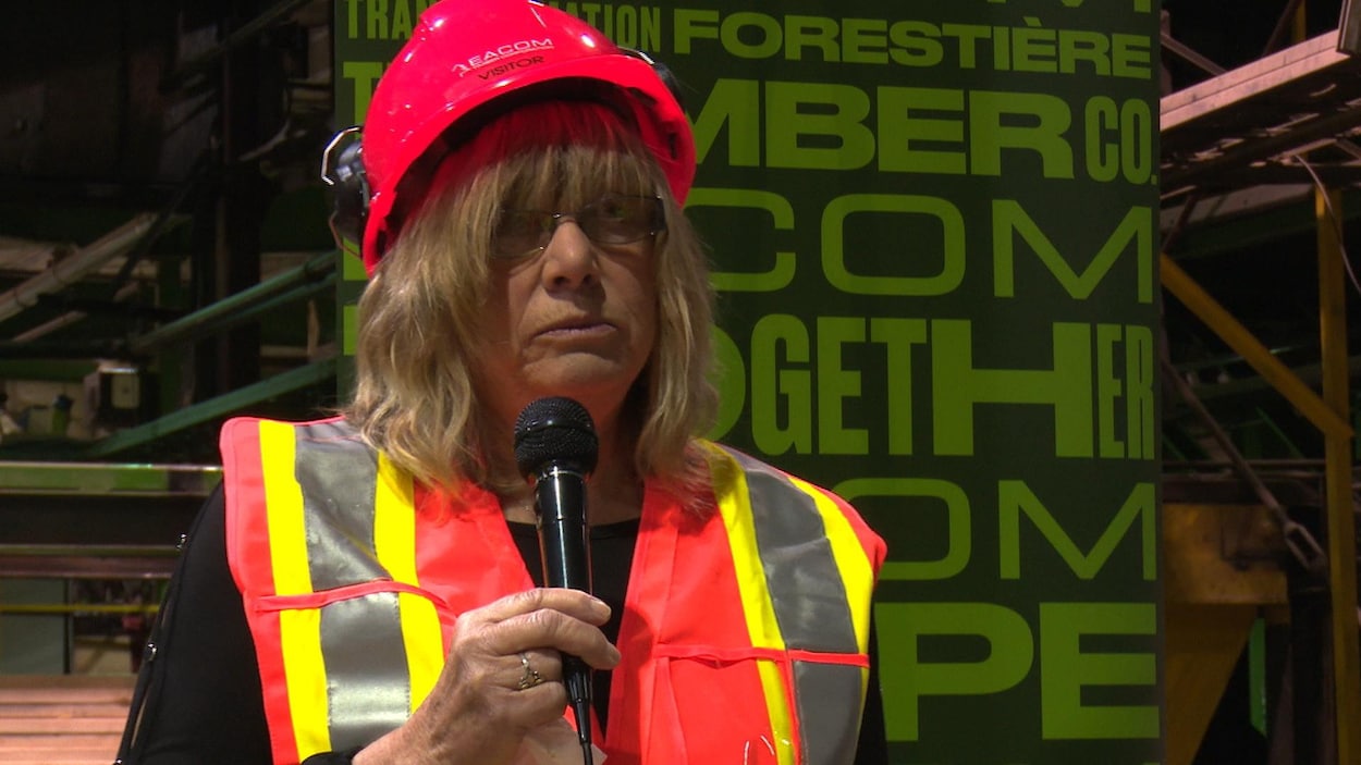 Joanne raconte son histoire devant une cinquantaine de travailleurs. Elle porte un casque de sécurité sur la tête.