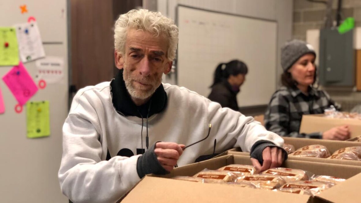 Un homme s'appui sur une boîte de nourriture.